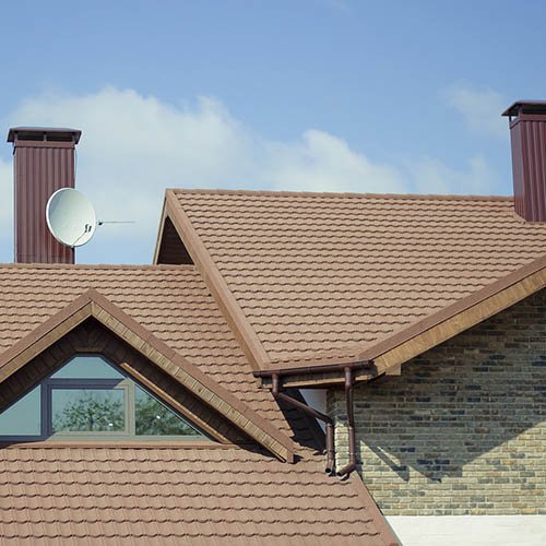 Technician installing solar panels on a residential rooftop under a clear blue sky.